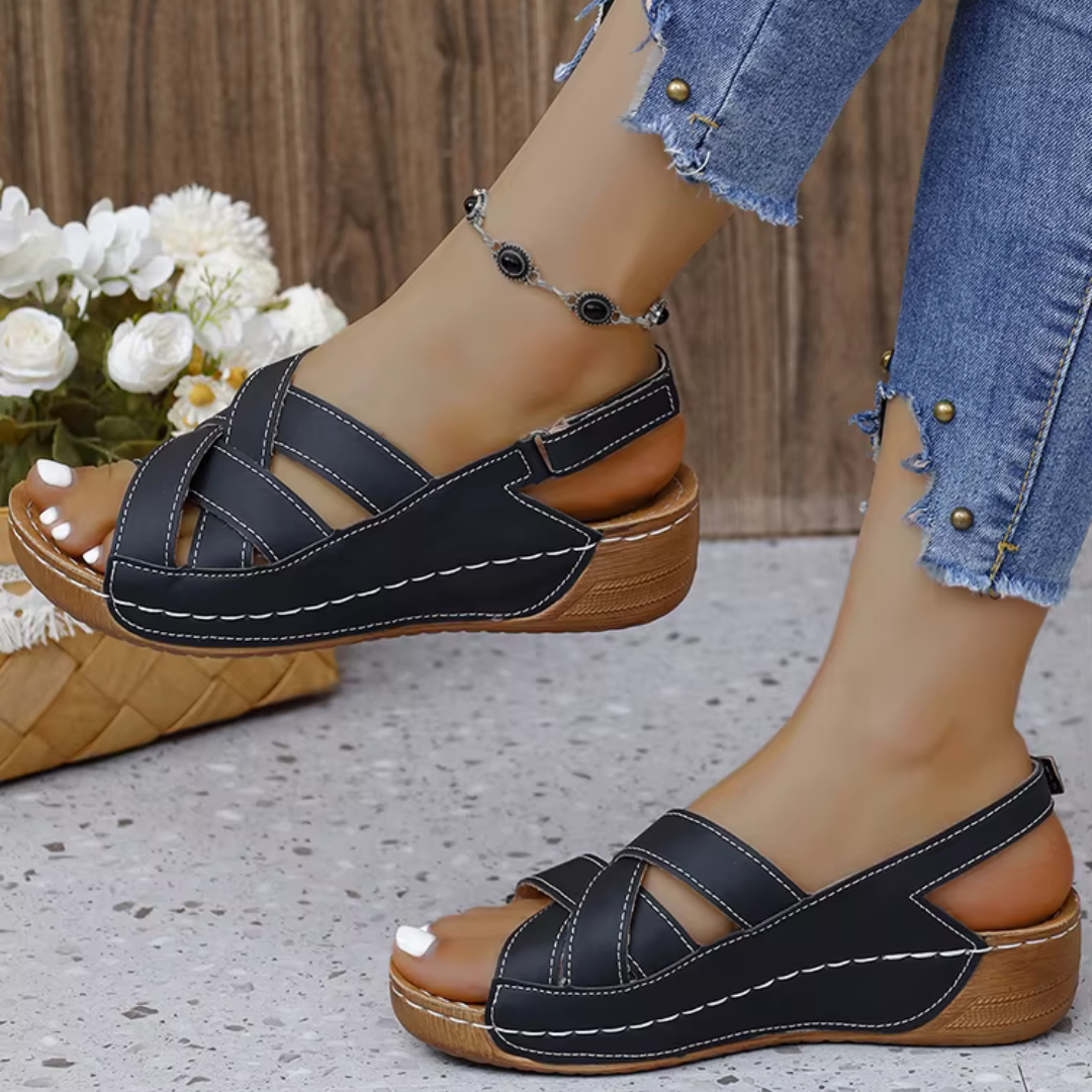Schwarze Damen-Sandalen mit Keilabsatz, Kreuzriemen und weißen Nähten, getragen mit zerrissenen Jeans. Perfekt für Sommermode und Freizeitoutfits.