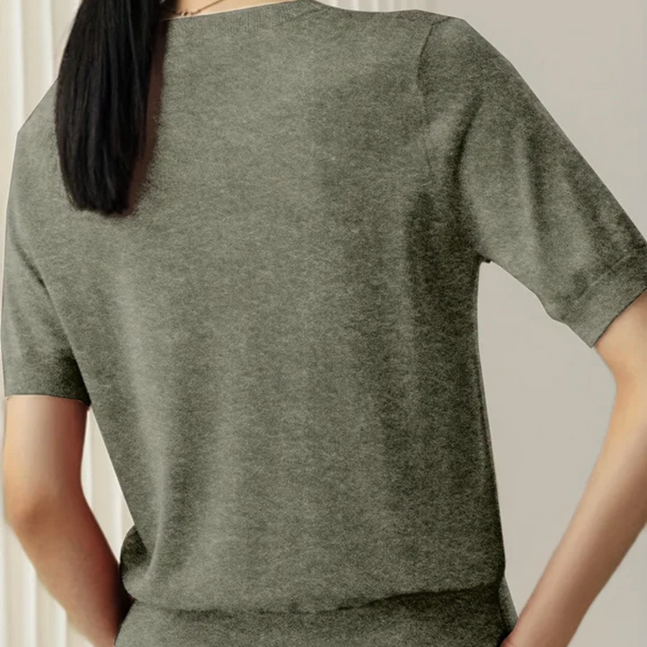 Rückansicht einer Frau in einem grauen T-Shirt aus Baumwolle, schlichtes Design, kurze Ärmel, glattes Haar, modische Freizeitkleidung.