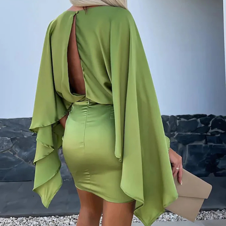 Frau in grünem, rückenfreiem Kleid mit weiten Ärmeln, hält eine beigefarbene Clutch. Elegantes Abendoutfit, modernes Design.