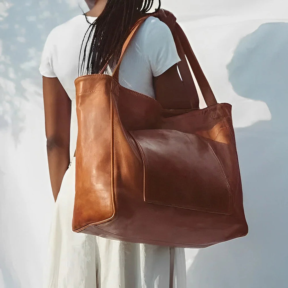 Frau mit großer brauner Ledertasche, weißem T-Shirt und Rock. Stilvolle, geräumige Handtasche, ideal für Alltag und Reisen.