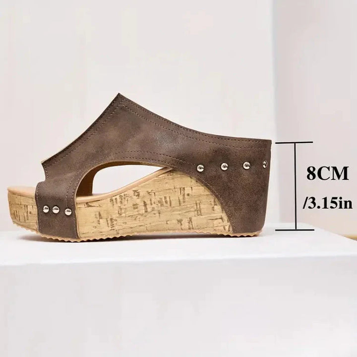 Braune Damen-Pantoletten mit 8 cm Keilabsatz aus Kork, seitlich genietet. Bequeme Sommerschuhe, modisch und vielseitig einsetzbar.