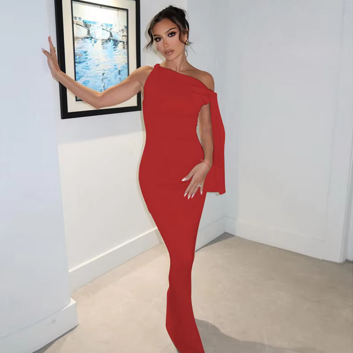 Eine Frau in einem eleganten, roten Abendkleid posiert vor einem gerahmten Bild an einer weißen Wand. Perfekt für Mode- und Abendkleid-Suchanfragen.