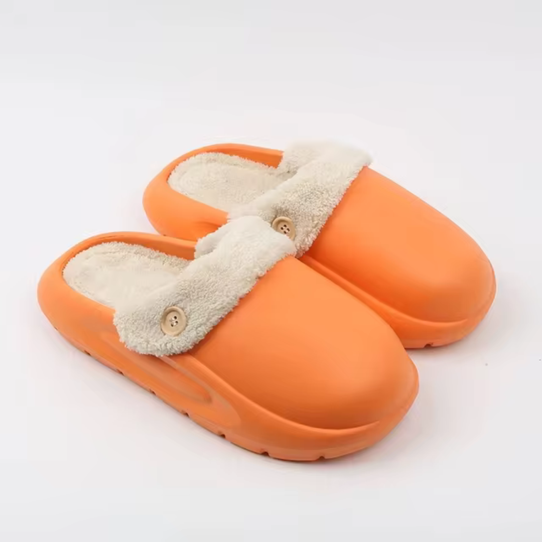 Orange Hausschuhe mit flauschigem Futter und Knopfdetail, ideal für gemütliche Winterabende. Bequeme, warme Pantoffeln für Zuhause.