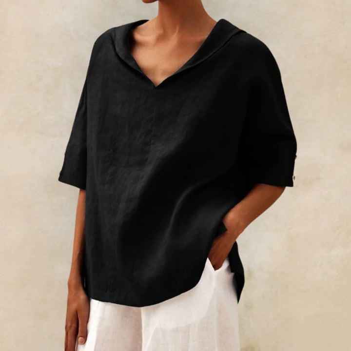 Frau trägt schwarzes Leinenhemd mit V-Ausschnitt und weißen Hosen. Minimalistischer, eleganter Look, ideal für Sommermode und Freizeitkleidung.