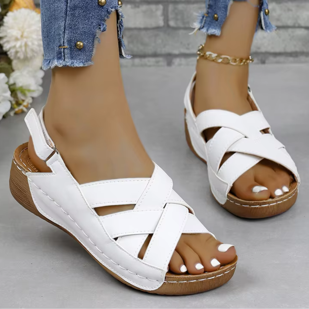 Weiße Damen-Sandalen mit Keilabsatz und Kreuzriemen, getragen mit zerrissenen Jeans. Bequeme Sommerschuhe für Damenmode.