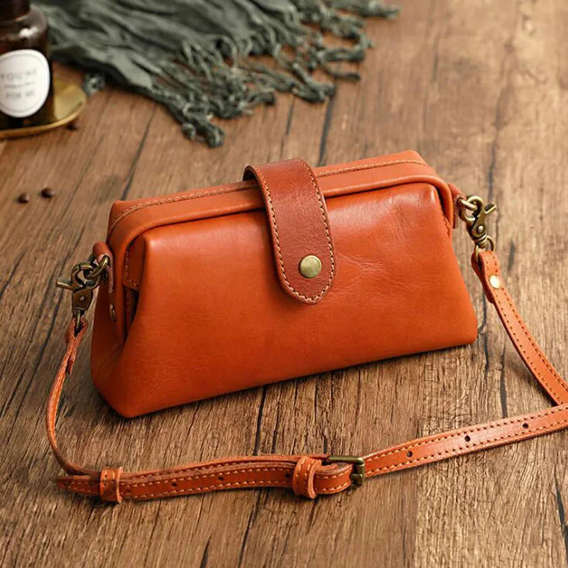 Braune Ledertasche auf Holztisch, Vintage-Design, mit verstellbarem Schulterriemen und Druckknopfverschluss, ideal für stilvolle Aufbewahrung.