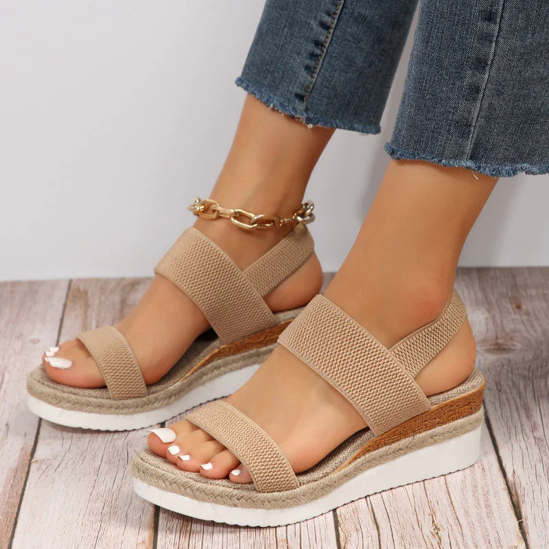 Beige Keilsandalen mit doppeltem Riemen, getragen mit blauen Jeans. Modische Sommerschuhe für Damen, ideal für Freizeit und Strand.