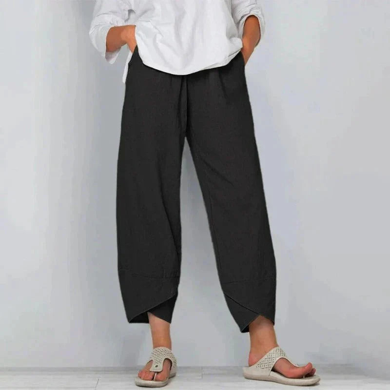Damenhose in Schwarz, locker geschnitten, kombiniert mit weißem Oberteil und Sandalen. Modetrend, bequeme Damenbekleidung, lässiger Stil.