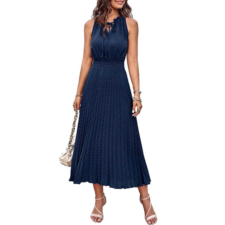 Frau in elegantem, ärmellosem, dunkelblauem Sommerkleid mit Plissee-Design, trägt Sandalen und eine Handtasche. Perfekt für Sommermode und Abendveranstaltungen.