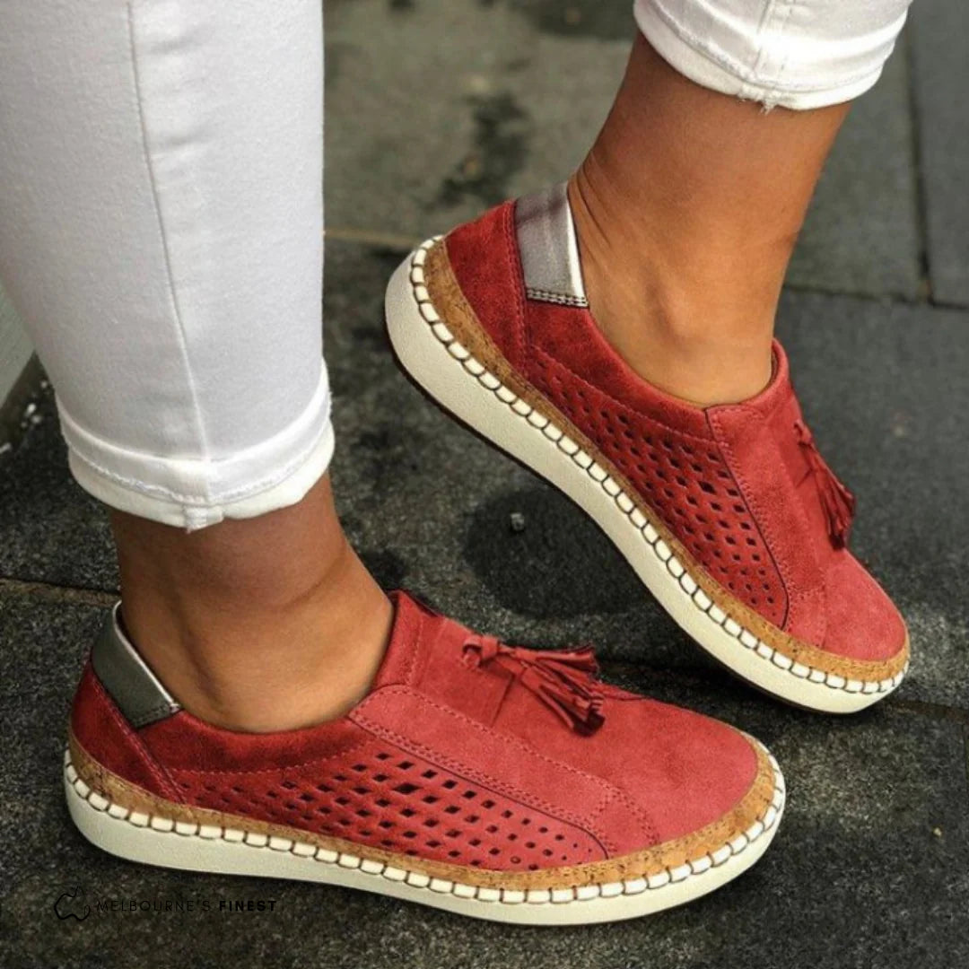 Rote Damen-Sneaker aus Wildleder mit Quasten und perforiertem Design, getragen zu weißen Jeans. Bequeme Freizeitschuhe für den Alltag.