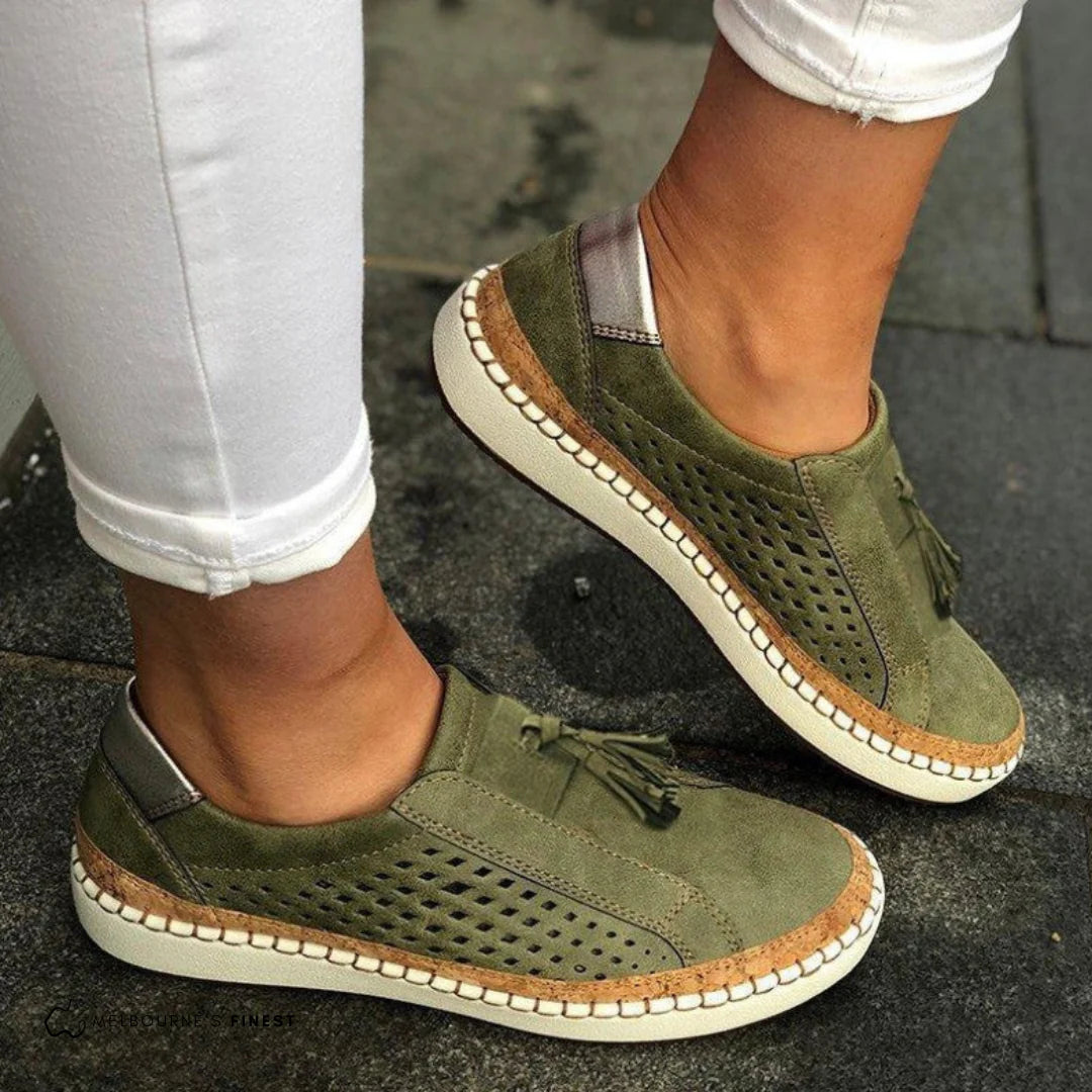 Grüne Damen-Sneaker mit Lochmuster und Fransen, kombiniert mit weißen Jeans. Bequeme Freizeitschuhe für den Alltag.