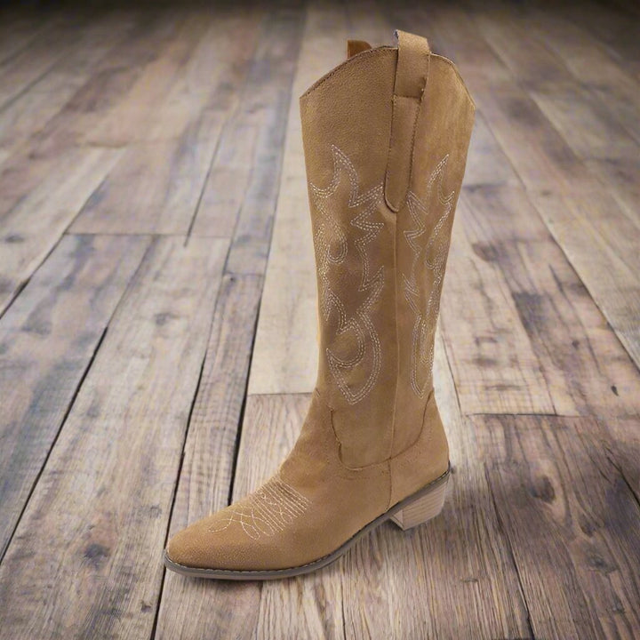 Ein einzelner brauner Cowboy-Stiefel aus Wildleder mit dekorativen Stickereien auf einem hölzernen Boden. Westernmode, Stiefel, Wildleder.