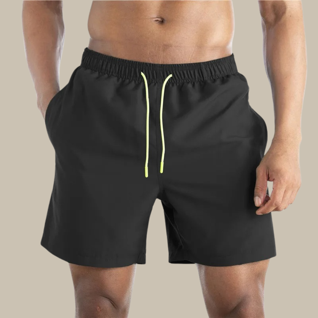 Mann trägt schwarze Sportshorts mit gelbem Kordelzug, ideal für Fitness und Freizeit. Bequeme Herren-Shorts, perfekt für Sport und Training.