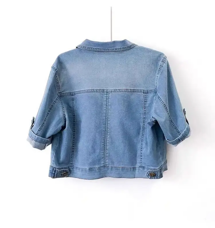 Rückansicht einer blauen Jeansjacke mit kurzen Ärmeln, lässiger Stil, aus Denim-Stoff, ideal für modische Freizeitoutfits.