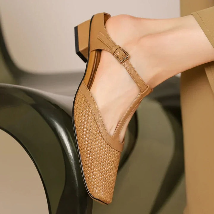 Beige Damen-Slingback-Schuhe mit geflochtenem Muster und Blockabsatz, getragen auf einem modernen Stuhl. Elegante, modische Sommerschuhe.