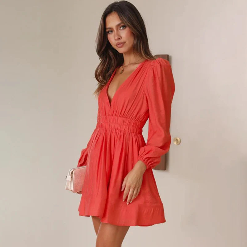 Frau in rotem Kleid mit tiefem V-Ausschnitt und langen Ärmeln, hält eine kleine Tasche. Elegantes Outfit, Mode, Damenbekleidung, Abendkleid.