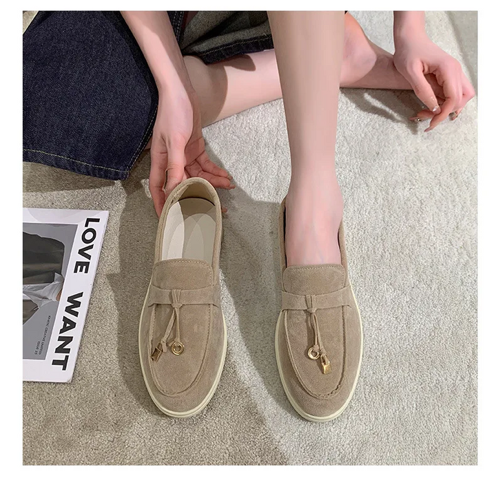 Beige Wildleder-Loafer mit Quasten, getragen von einer Person auf Teppichboden. Modische Freizeitschuhe, ideal für stilvolle Outfits und Komfort.