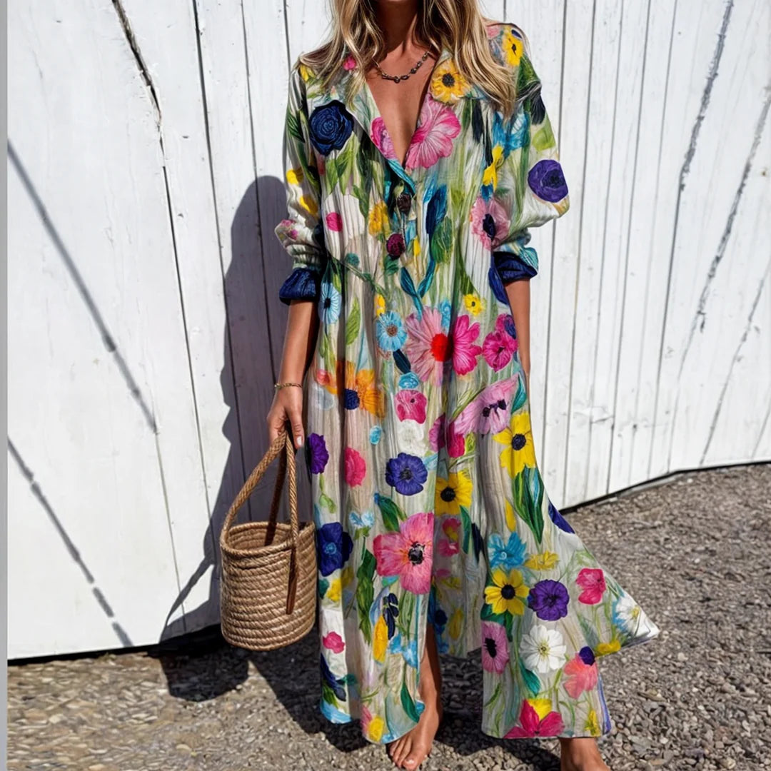 Frau in langem, geblümtem Kleid vor weißer Holzwand, hält geflochtene Korbtasche. Sommermode, florales Design, Freizeitkleidung.