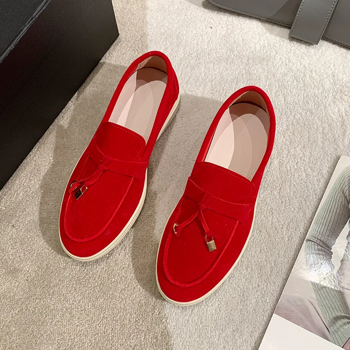 Rote Wildleder-Loafer mit weißer Sohle auf beigem Teppich, elegantes Design, modische Herrenschuhe, stilvolle Freizeitmode.