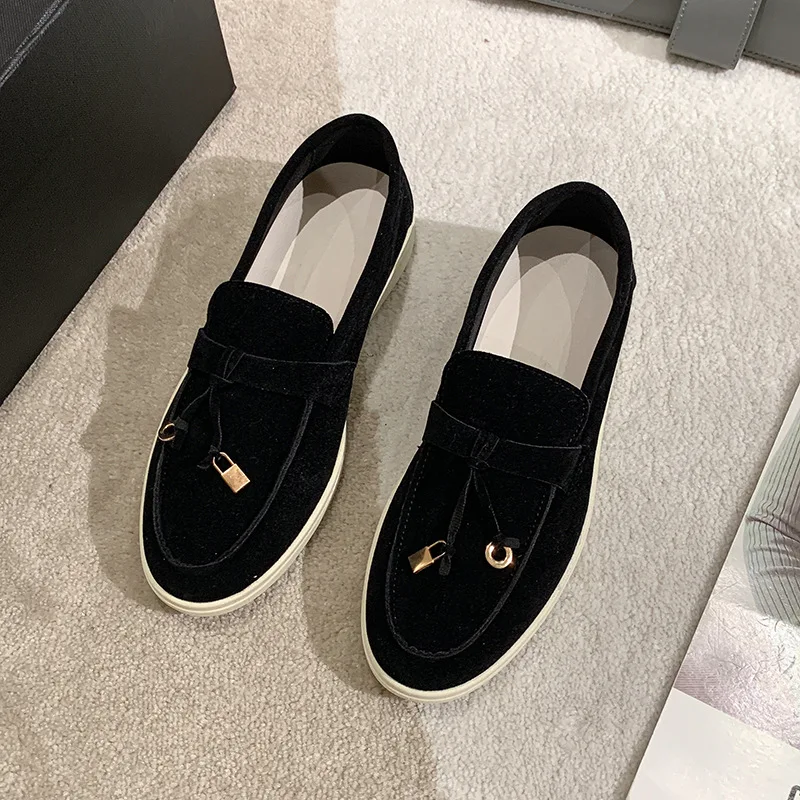 Schwarze Samt-Loafer mit goldenen Verzierungen auf beigem Teppich. Elegante Herrenschuhe, modisch und stilvoll, ideal für formelle Anlässe.