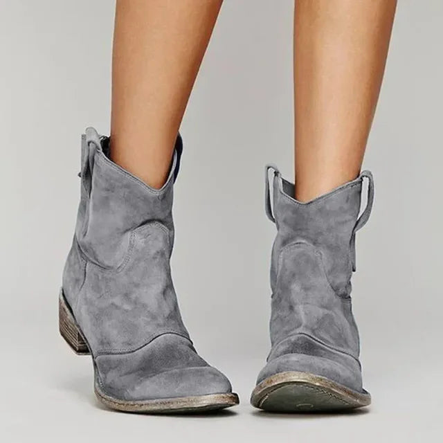 Graue Cowboystiefel aus Wildleder, getragen von einer Person. Modische Damenstiefel, ideal für Herbst-Outfits. Bequeme, stilvolle Schuhe.