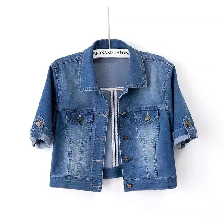 Blauer Jeansjacke mit kurzen Ärmeln, Knopfleiste und Brusttaschen, aufgehängt an einem Kleiderbügel. Modische Damenbekleidung, lässiger Stil.