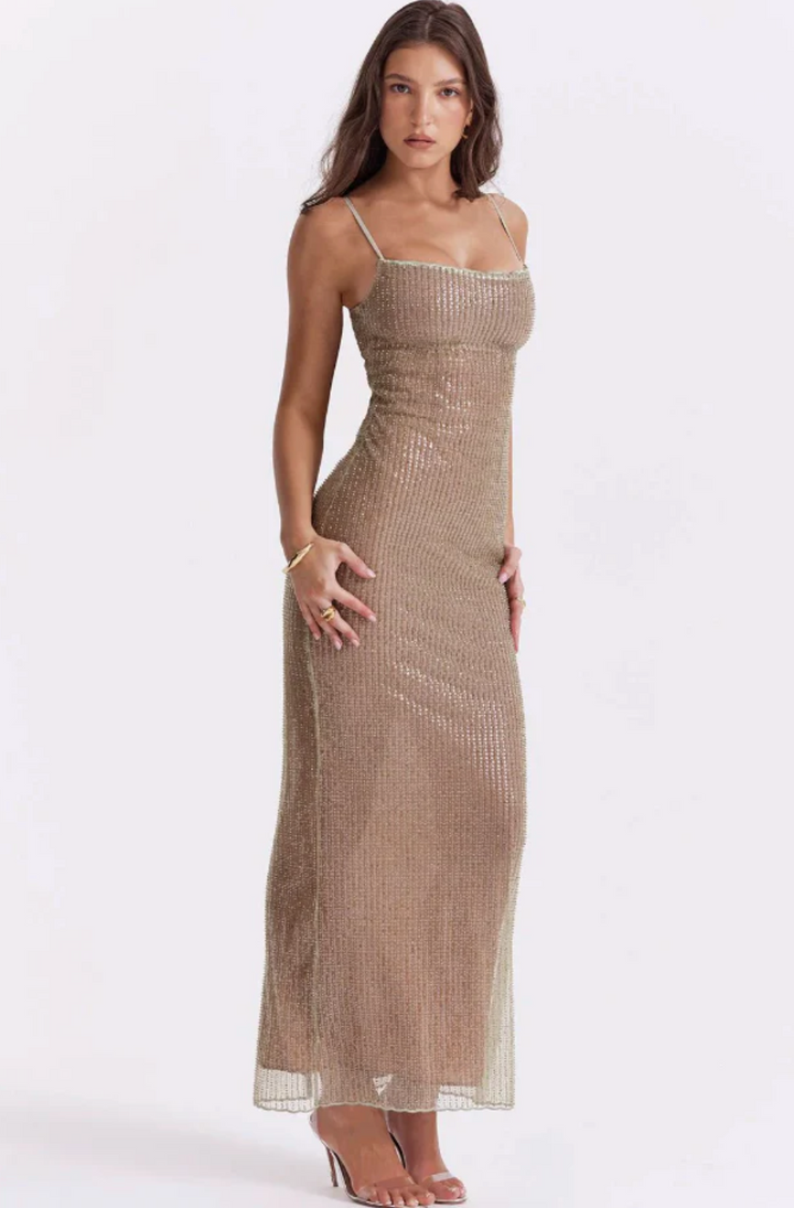 Frau in einem eleganten, goldenen Abendkleid mit Spaghettiträgern, stehend vor weißem Hintergrund. Mode, Abendgarderobe, Damenbekleidung.