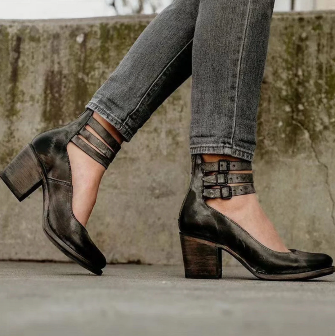 Schwarze Lederpumps mit Blockabsatz und Riemchen, getragen zu grauen Jeans. Modische Damenschuhe, ideal für Herbstmode und urbanen Stil.