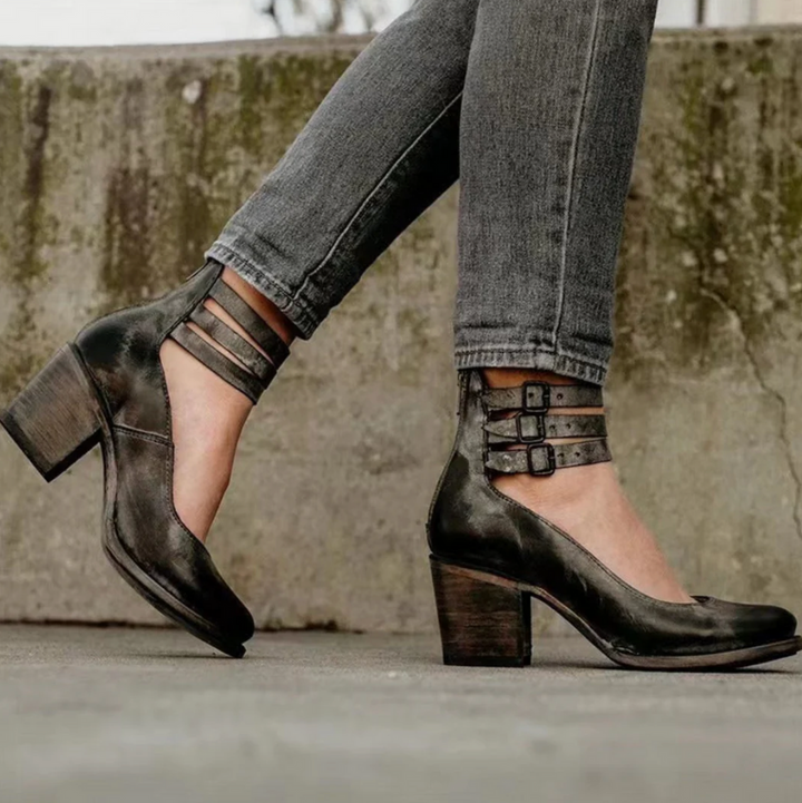 Schwarze Lederpumps mit Blockabsatz und Riemchen, getragen zu grauen Jeans. Modische Damenschuhe, ideal für Herbstmode und urbanen Stil.