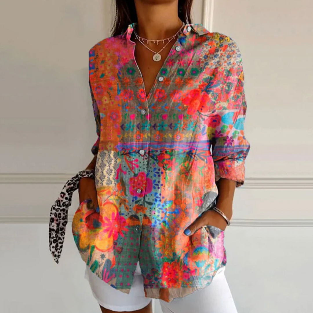 Frau trägt bunte, florale Bluse mit Knopfleiste und weißen Shorts. Modetrend, Damenmode, Sommeroutfit, lässiger Stil, farbenfrohes Design.