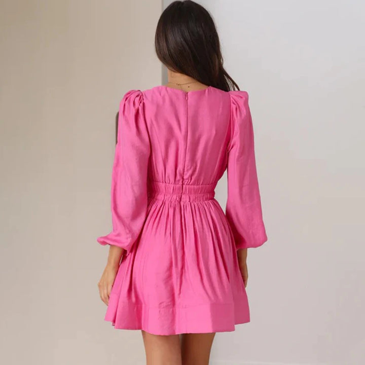 Frau in rosa Kleid mit langen Ärmeln, Rückansicht. Modetrend, elegantes Damenkleid, stilvolle Abendmode, femininer Look.