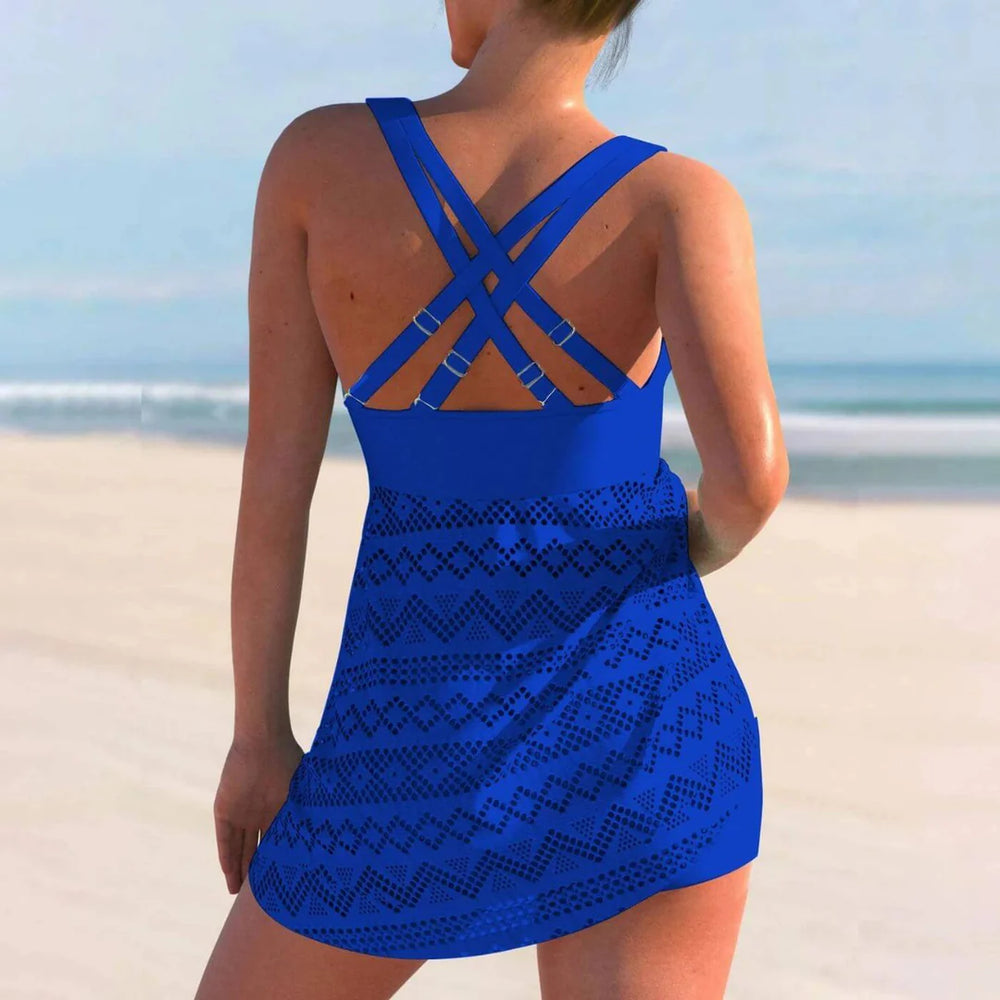Frau in blauem Badeanzug mit Kreuzträgern am Strand, Sommermode, Strandkleidung, Rückenansicht, Meereshintergrund, Urlaub, Bademode.