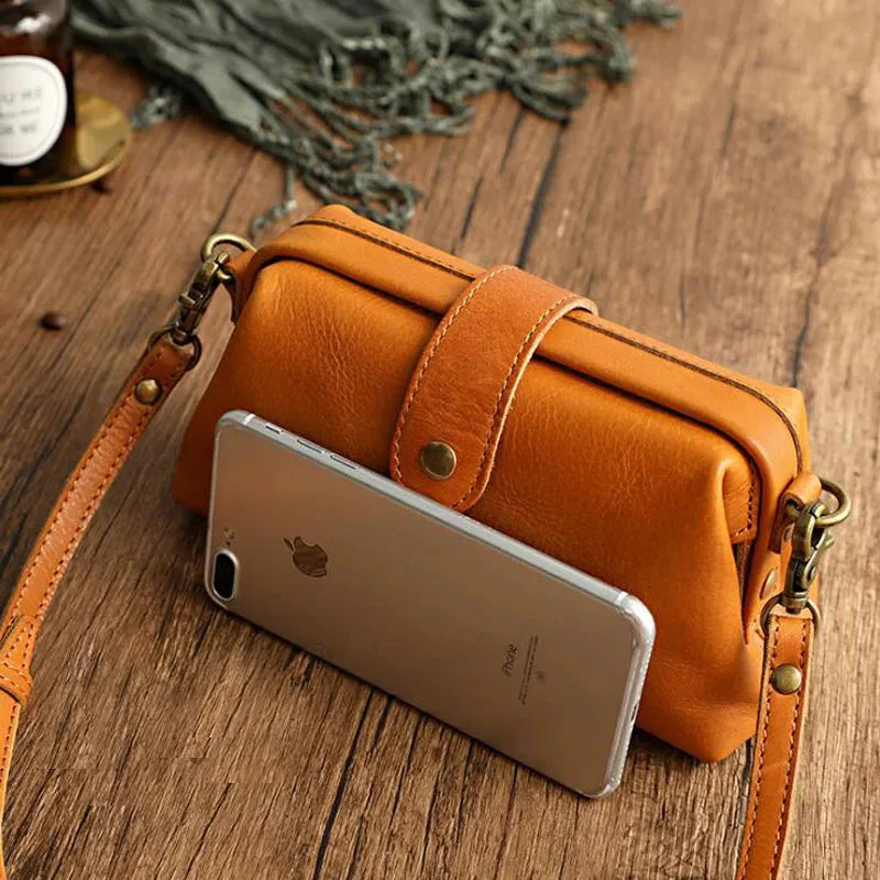 Orange Ledertasche mit Smartphone auf Holztisch, modisches Accessoire, Damenhandtasche, Vintage-Stil, ideal für Alltag und Reisen.