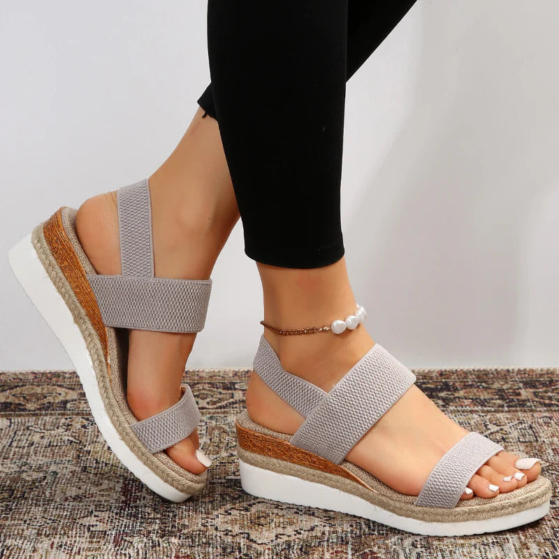 Damen Sandalen mit Keilabsatz, beige, elastische Riemen, auf Teppich. Modische Sommerschuhe, bequem, ideal für Freizeit und Alltag.