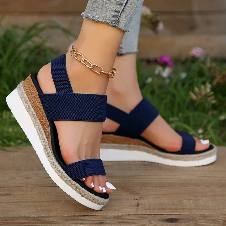 Damen Sandalen mit Keilabsatz, blauem Stoff, weißer Sohle und goldener Fußkette. Sommermode, bequeme Schuhe, trendige Accessoires.