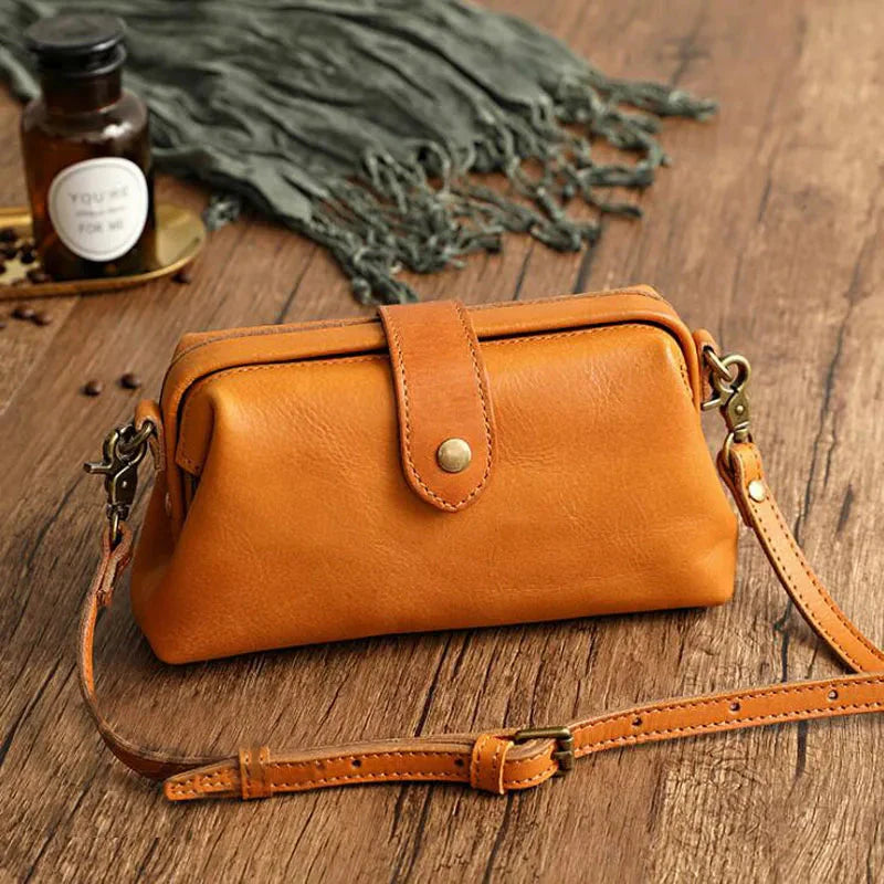 Braune Ledertasche mit Schnalle auf Holztisch, umgeben von Dekorationen. Stilvolle Umhängetasche, ideal für Damenmode und Accessoires.