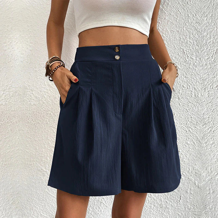 Frau in weißem Top und blauen, hoch taillierten Shorts mit Taschen, modisch, Sommerkleidung, lässiger Stil, Damenmode, Texturdetails.