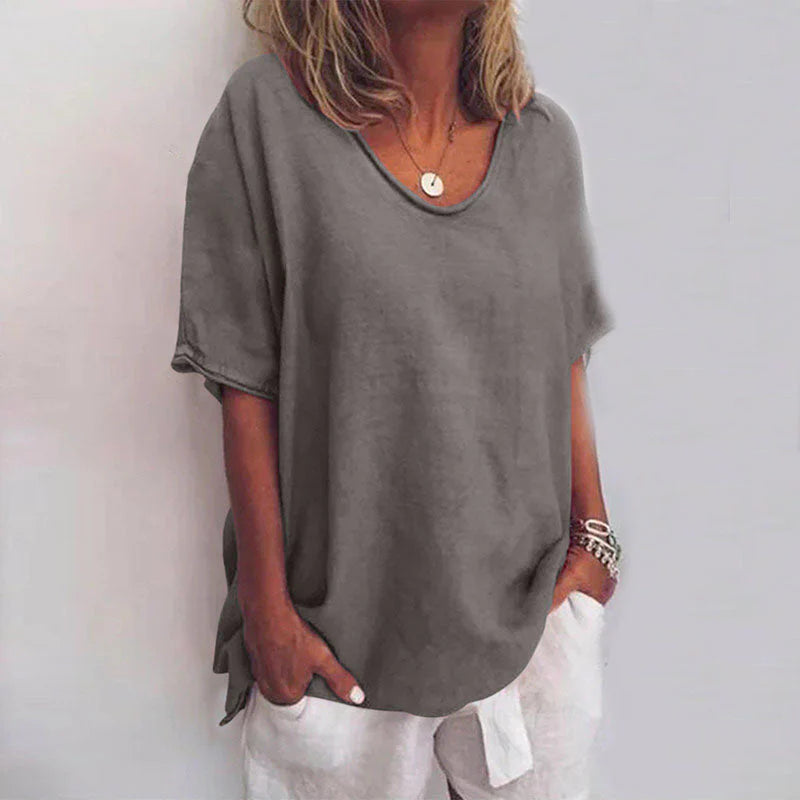 Frau in grauem Oversize-T-Shirt und weißen Shorts, lässiger Sommerlook, modische Damenbekleidung, entspannter Stil, Schmuckaccessoires.