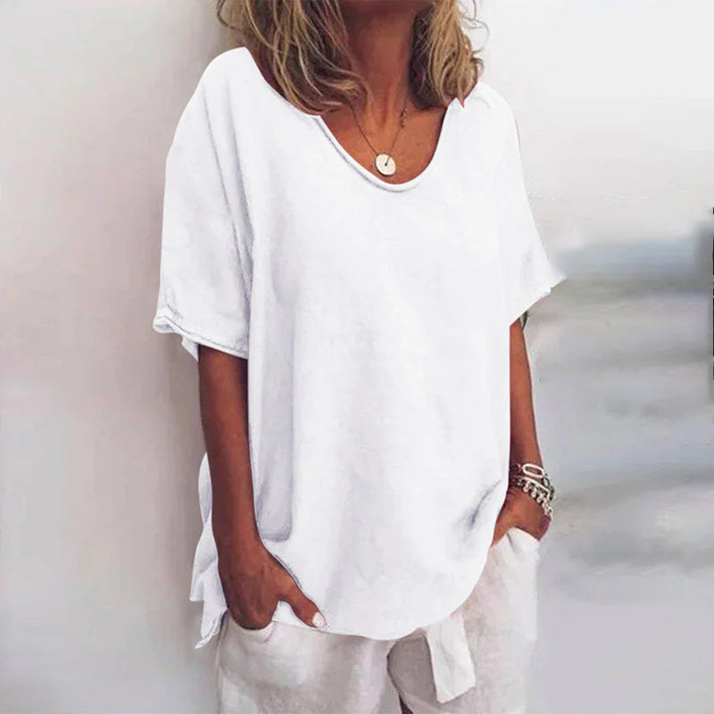 Frau in weißem, lockerem T-Shirt und Hose, lässiger Sommerlook, modisches Outfit, minimalistisch, entspannt, Schmuckaccessoires.