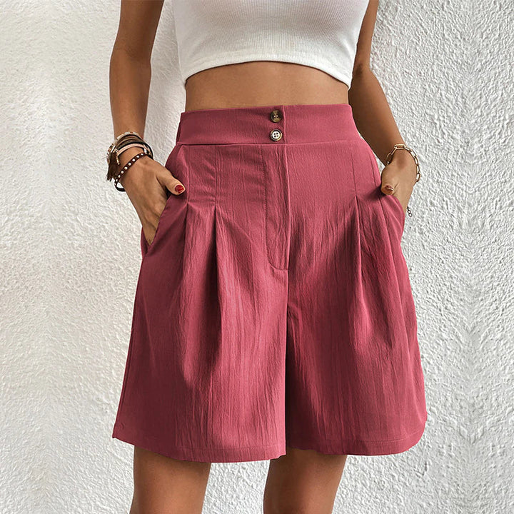 Frau trägt rote, hoch taillierte Shorts mit Knöpfen und Taschen, kombiniert mit weißem Top. Sommermode, Damenbekleidung, lässiger Stil.