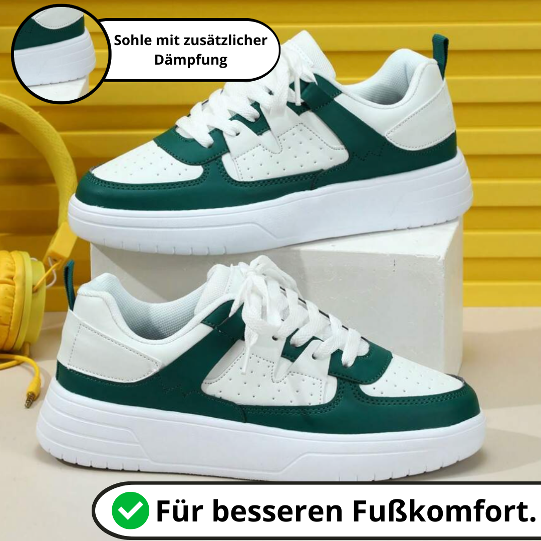 Weiße und grüne Sneaker mit zusätzlicher Dämpfung, auf weißem Podest vor gelbem Hintergrund. Bequeme Sportschuhe für optimalen Fußkomfort.