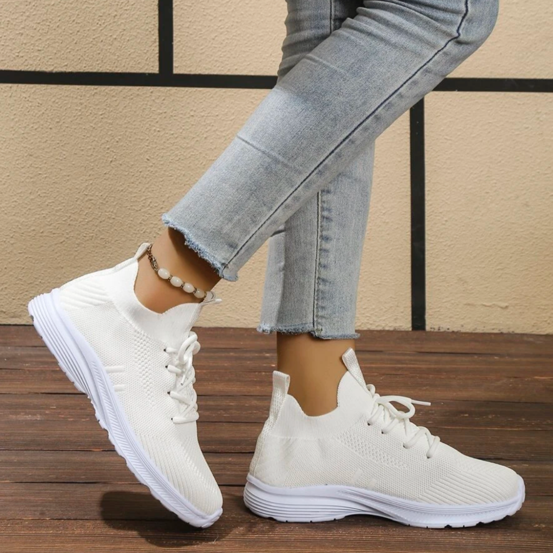 Damen tragen weiße Sneaker mit Strickmuster und blauer Jeans. Bequeme, modische Schuhe für Freizeit und Sport. Perfekt für den Alltag.