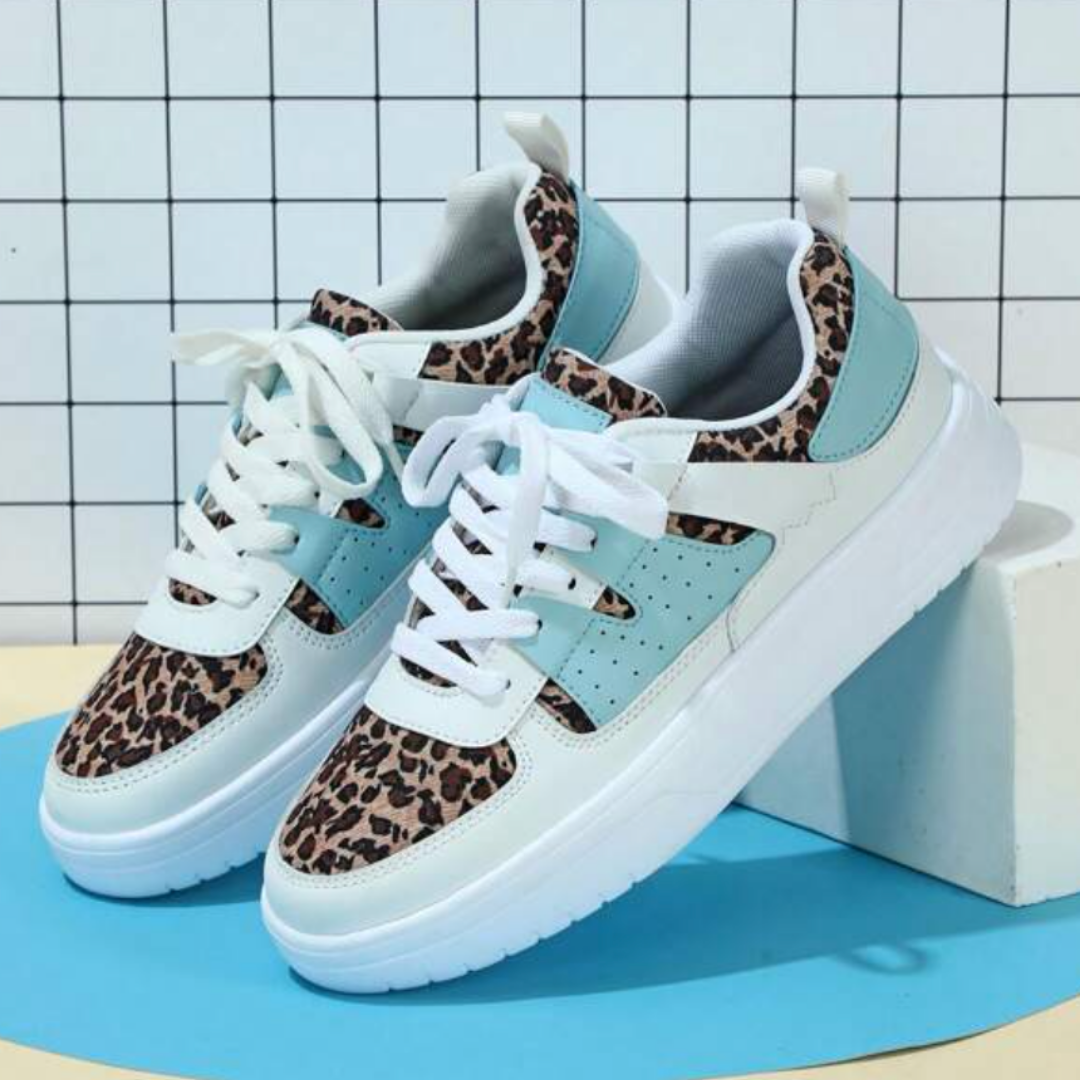 Leopard-Sneaker mit weißer Sohle und türkisfarbenen Akzenten vor kariertem Hintergrund. Modische Turnschuhe, trendiges Design, Damenmode.