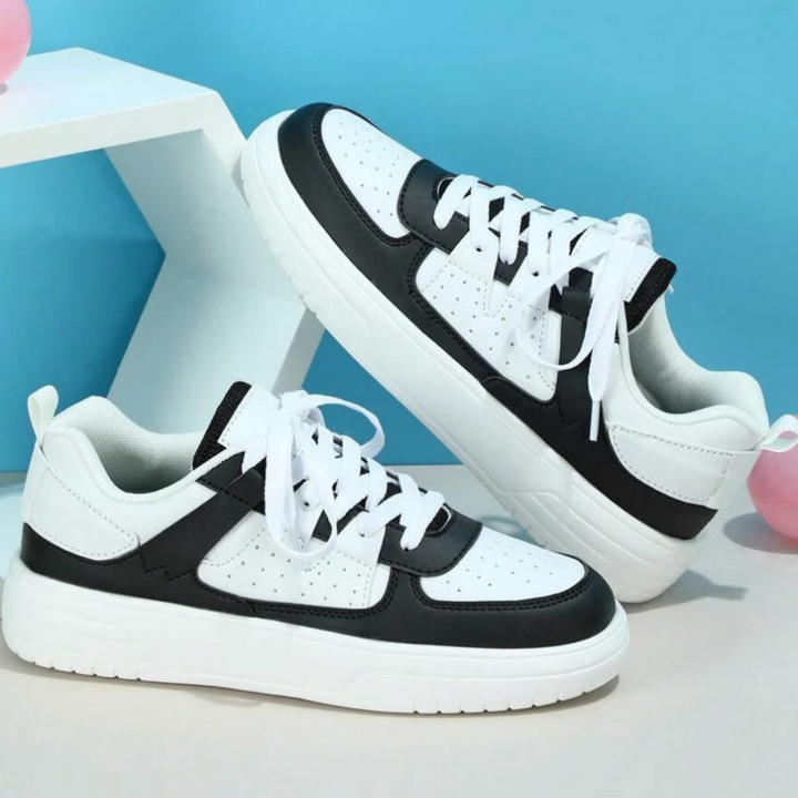 Weiße und schwarze Sneaker auf blauem Hintergrund, moderne Sportschuhe, stilvolles Design, bequeme Turnschuhe für Herren und Damen.